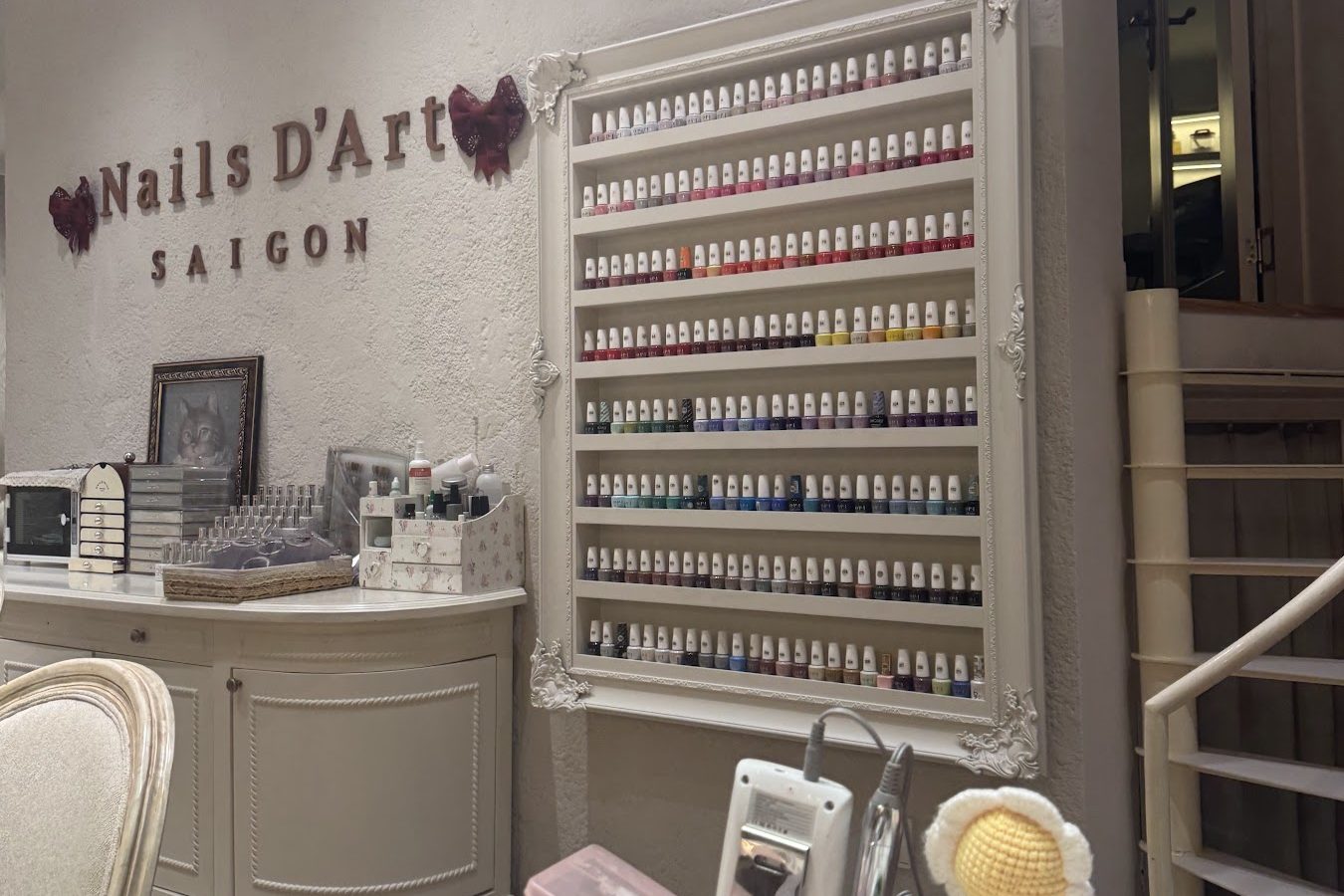 Rows of polish bottles racked inside an ornate white frame on the stucco wall.