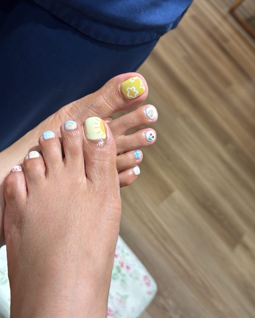 A pedicure in soft white with a painted accent toe.