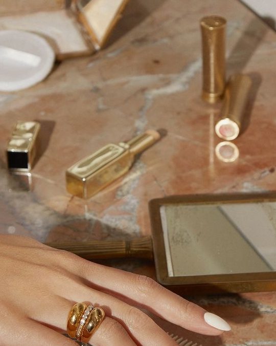 Bare almond nails and gold rings on the marble work table.