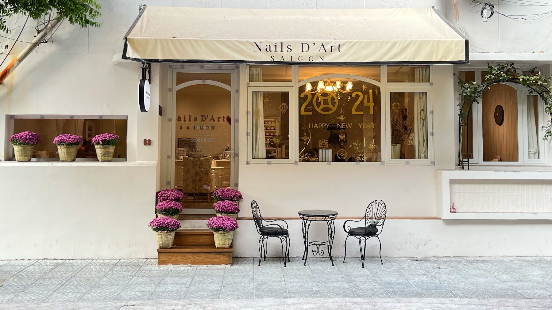 The shop front on Huynh Thuc Khang, a cream awning, iron cafe chairs and pots of pink chrysanthemums on the steps.