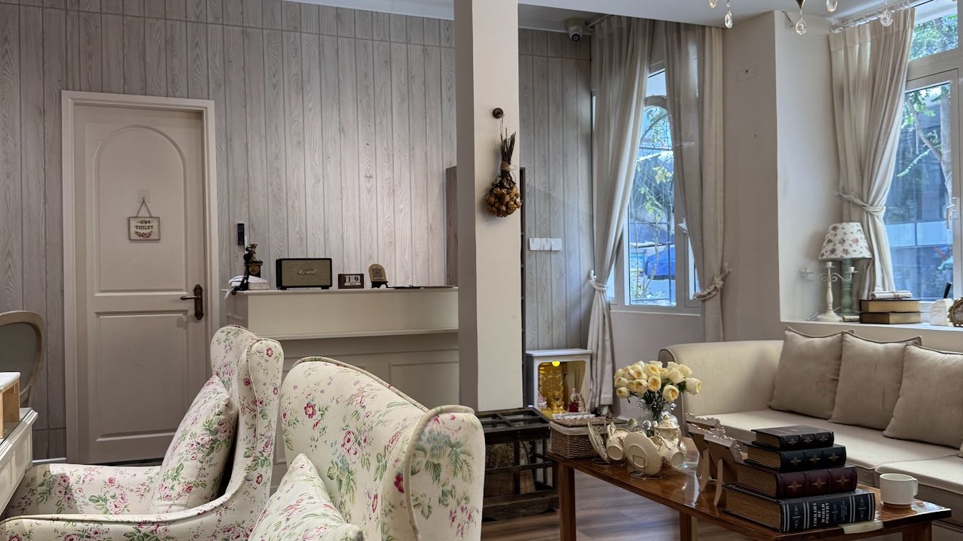 Floral upholstered wing chairs and cream painted furniture on the wooden floor.